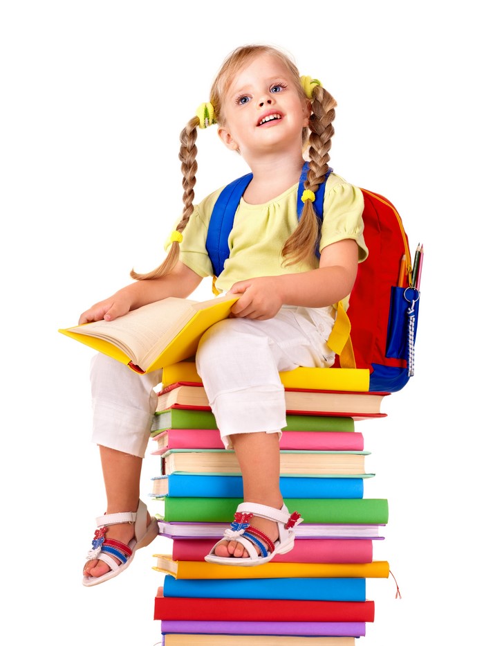Little girl with braids sitting on books with backpack