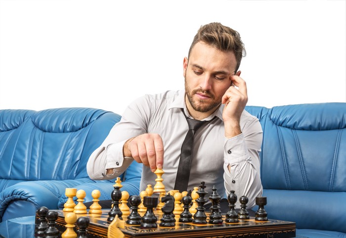 Man playing chess on a blue couch