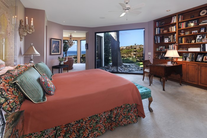 Bedroom with a large bed, bookshelves, and ocean view