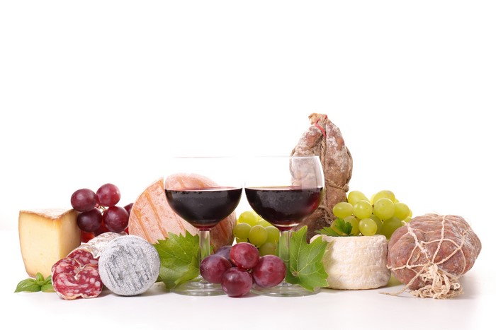Still life of wine, cheese, grapes, and cured meats