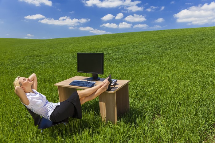 Blonde woman relaxing at a desk in a grassy field