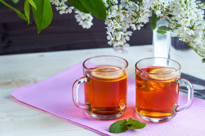 Two cups of tea with lemon and flowers