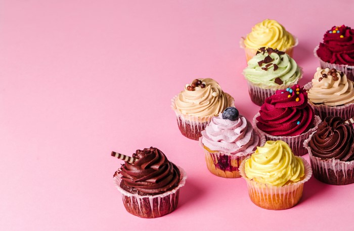 Assortment of colorful cupcakes on a pink background