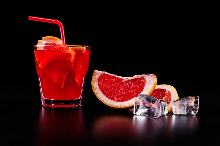 Grapefruit cocktail with ice and slices on black background