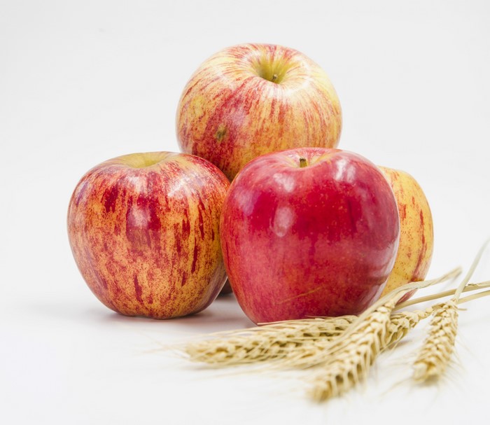 Four apples and wheat ears on white background