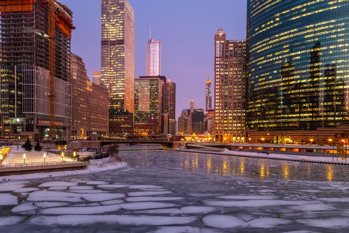 Chicago city skyline over frozen river at dusk