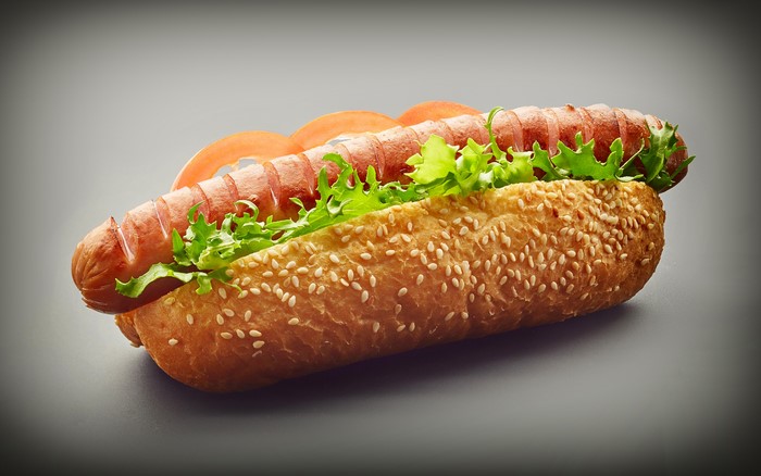 Hot dog with lettuce and tomato in a sesame seed bun