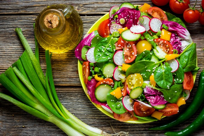 Salad with vegetables and olive oil on wooden planks