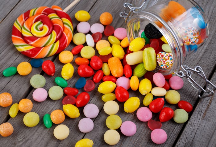 Assortment of colorful candies and a lollipop on wooden planks
