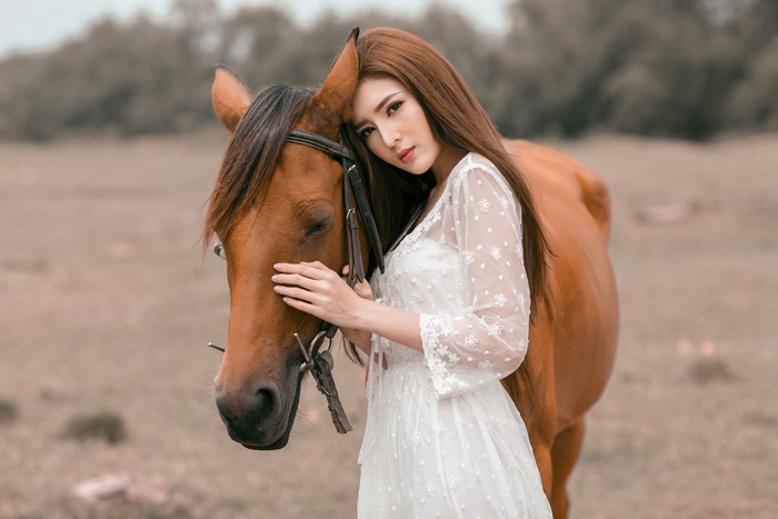 Asian woman in white dress with brown horse