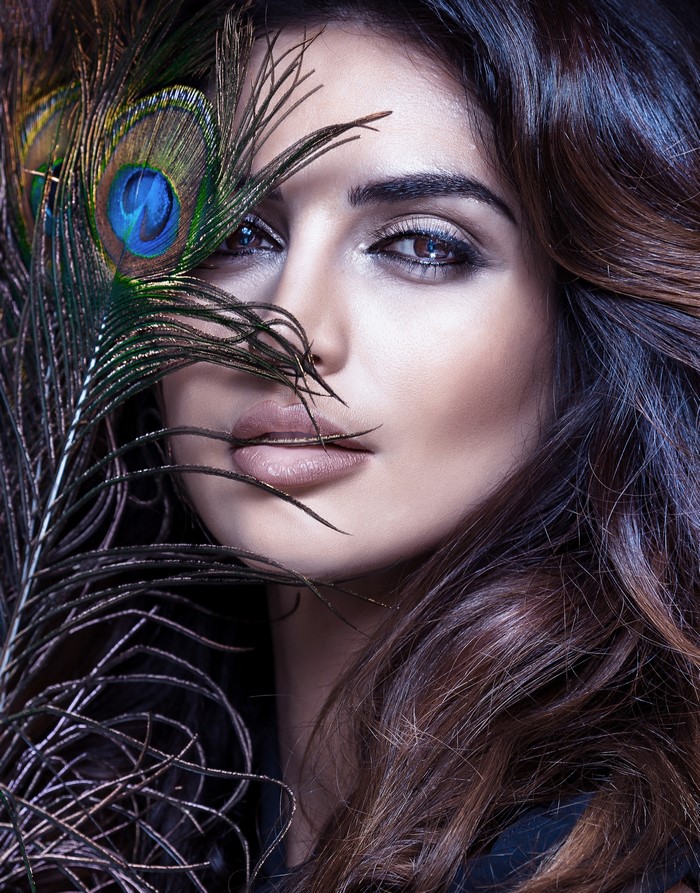 Woman with peacock feather covering face