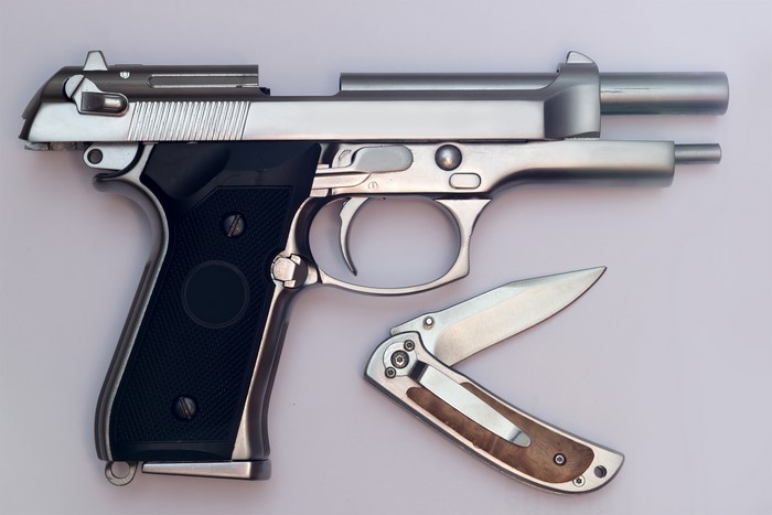 Pistol and folding knife on gray background