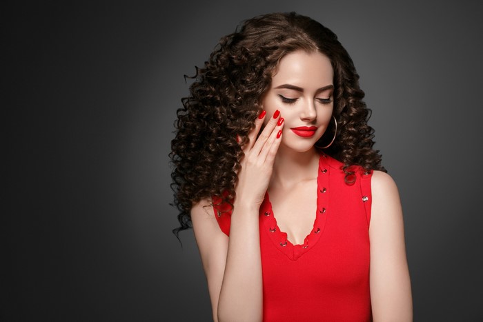Woman with curly brown hair and red lipstick