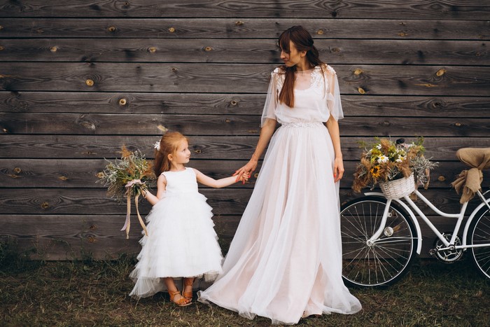 Bride and flower girl with bouquets and bicycle