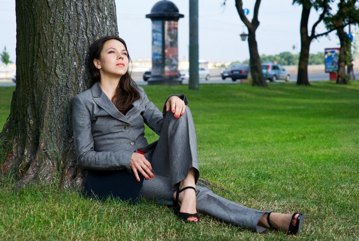 Woman in suit sitting by a tree