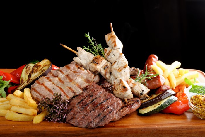 Meat platter with grilled meats, vegetables, and fries