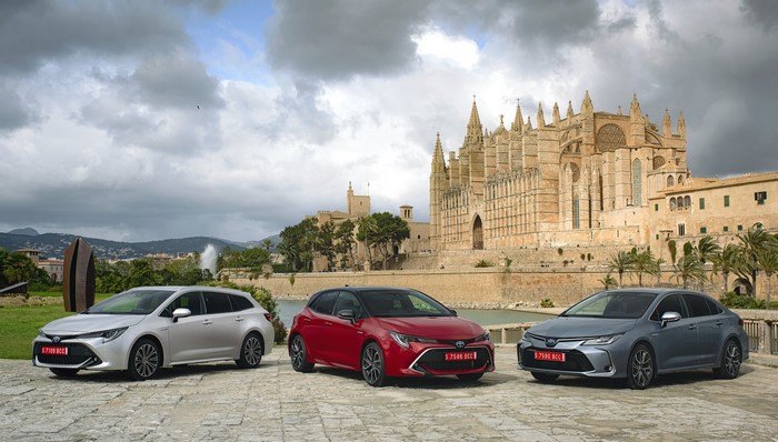 Three Toyota Corolla cars in front of a cathedral