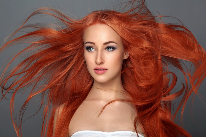 Redhead girl with flowing hair on gray background