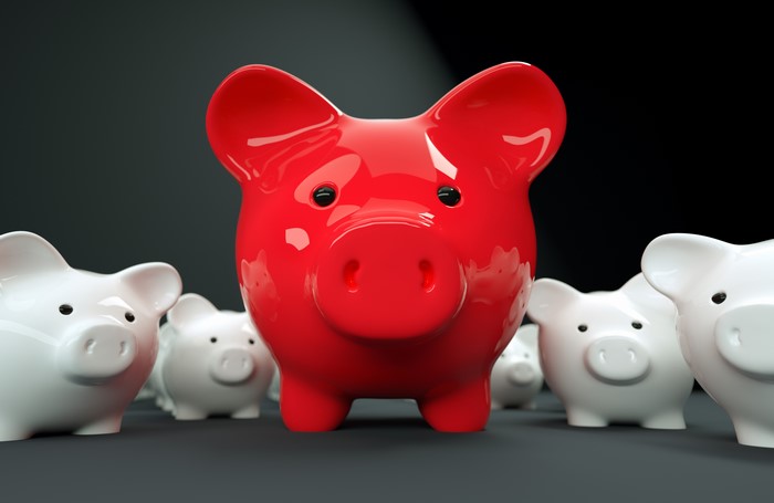Red piggy bank in front of white piggy banks