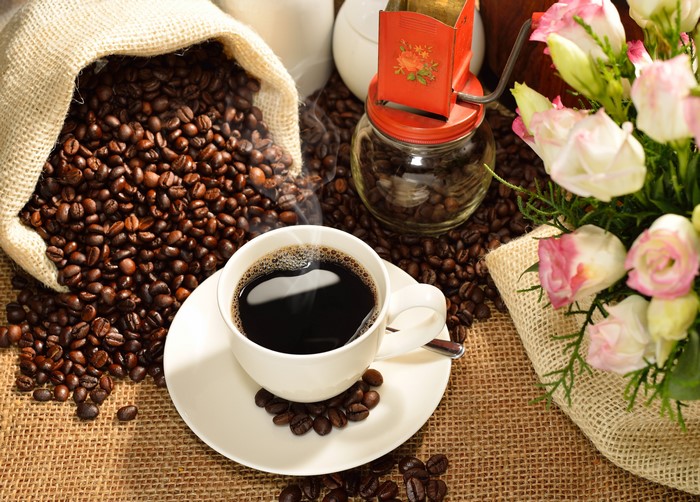 Coffee beans, cup of coffee, and flowers