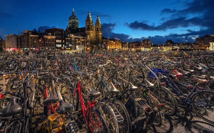 Bicycles parked in front of a church in Amsterdam at dusk
