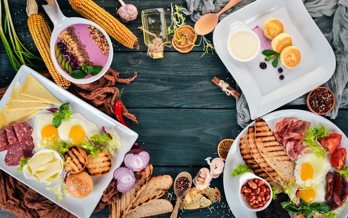 Breakfast spread with fried eggs, sausages, cheese, and pancakes
