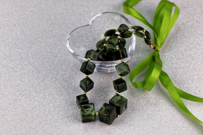 Green stone necklace in heart-shaped bowl with ribbon