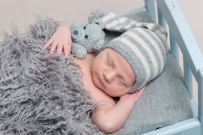 Newborn baby sleeping with teddy bear and winter hat