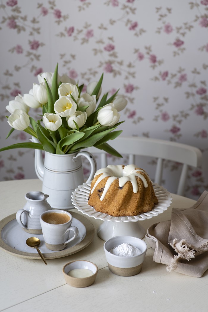 Bundt cake with white icing, tulips, and coffee