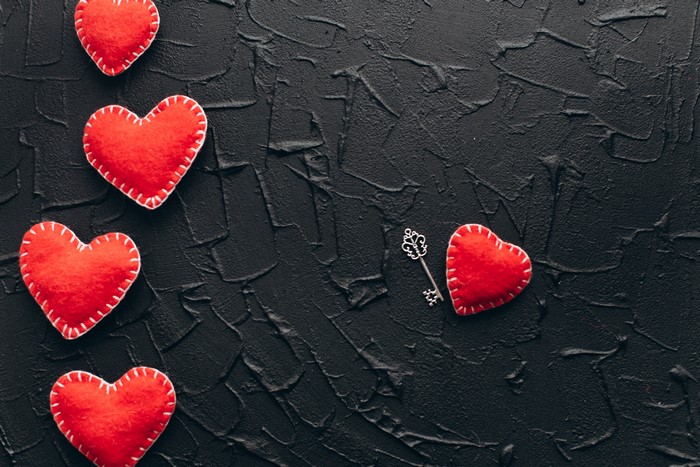 Red hearts and a key on a black textured background