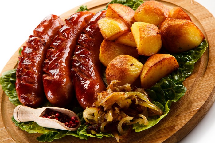 Sausages and roasted potatoes on a cutting board