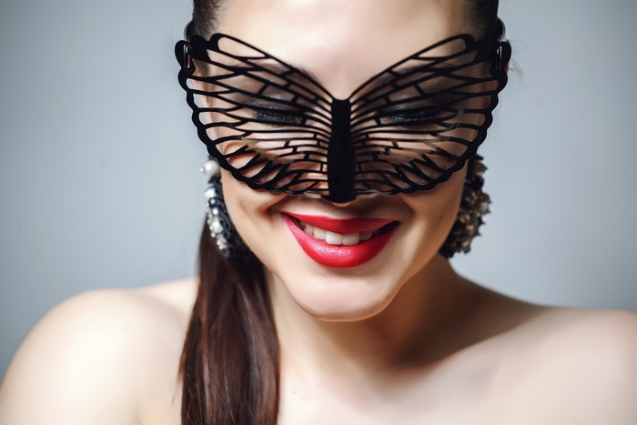 Woman wearing a black butterfly mask and red lipstick