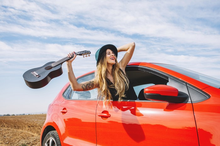 Woman with guitar in a red car