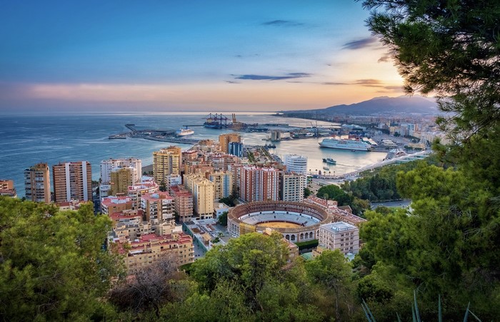 Malaga cityscape with harbor and bullring at sunset