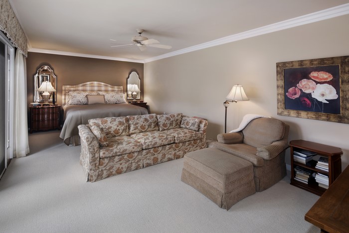 Bedroom with bed, sofa, armchair, and lamps