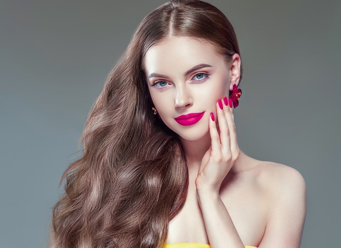 Woman with brown wavy hair and pink lipstick