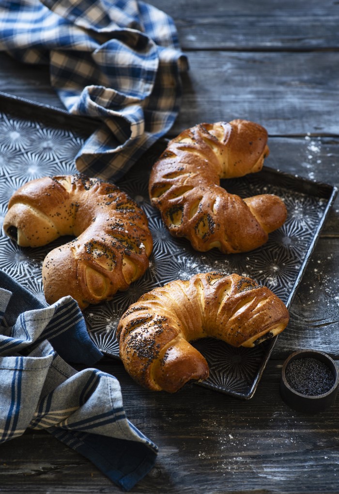 Three crescent-shaped pastries with poppy seeds on a tray