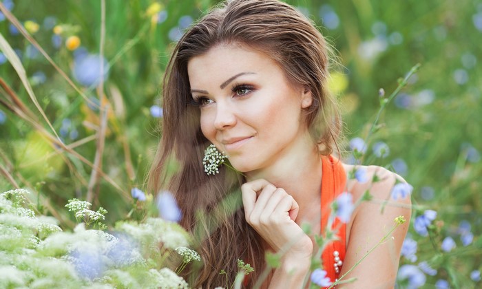 Brown haired woman smiling in a field of flowers