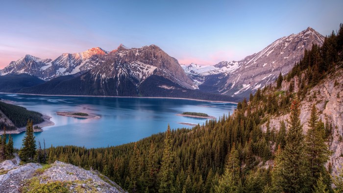 Mountains and lake with pine forests at sunrise