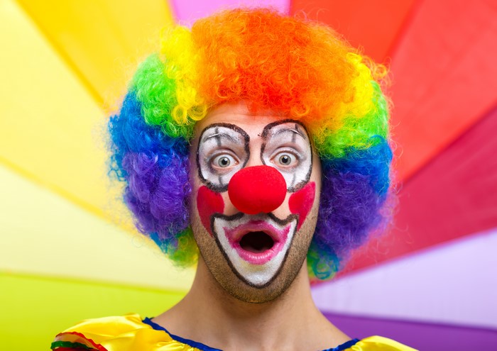 Man with clown makeup and rainbow wig