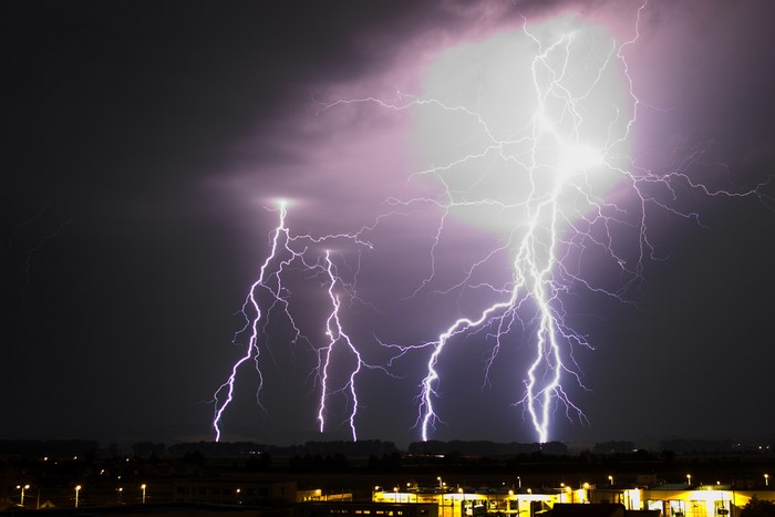 Multiple lightning strikes over a city at night