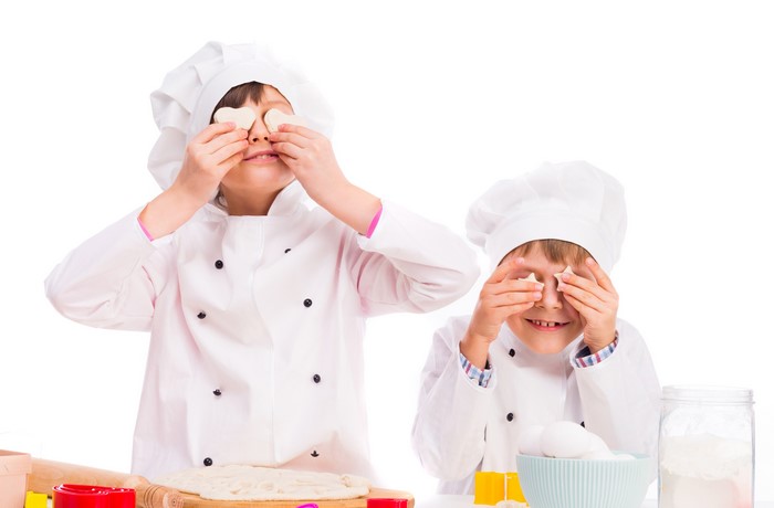 Two young chefs covering eyes with cookies