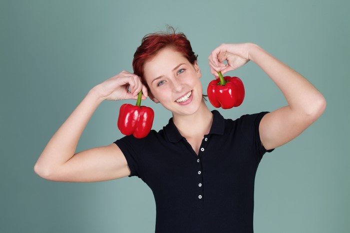 Redhead girl holding red bell peppers