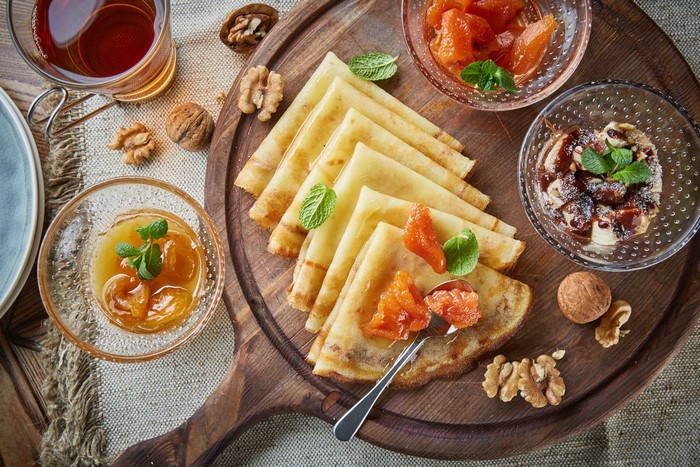Pancakes with jam and walnuts on a wooden board