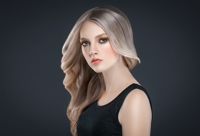 Blonde woman with wavy hair on gray background