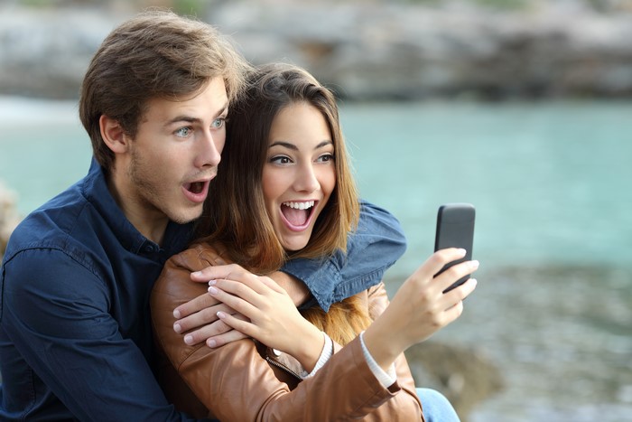 Couple looking at smartphone with surprise