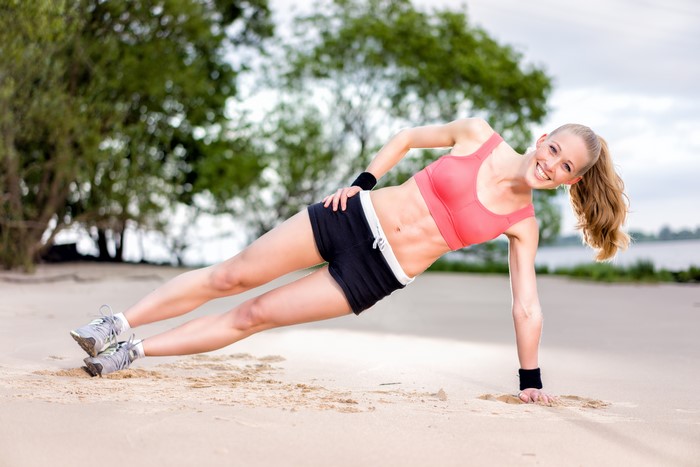 Woman doing side plank on beach