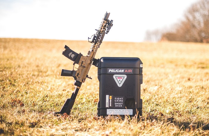 AR15 rifle and Pelican Air case on grass