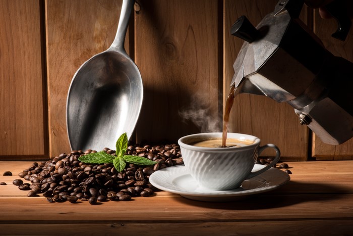 Coffee beans, scoop, and coffee being poured into a cup