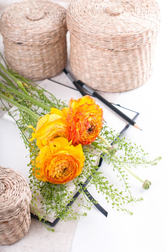 Yellow Ranunculus flowers on a notebook with baskets
